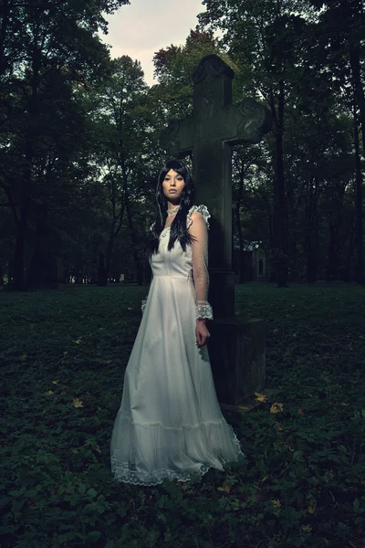 Witch from the cemetery, in front of cross — Stock Photo, Image