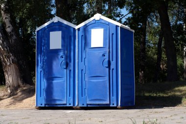 Two portable toilet cabins in park at dry sunny summer da
