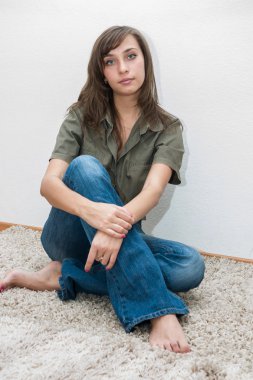 Beyaz bir halı üzerinde oturan genç kız