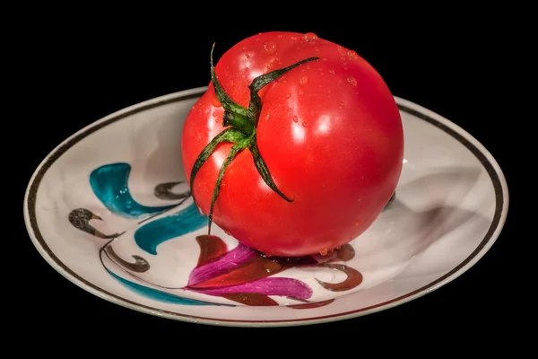 Red tomato on a saucer on a black background — Stock Photo, Image