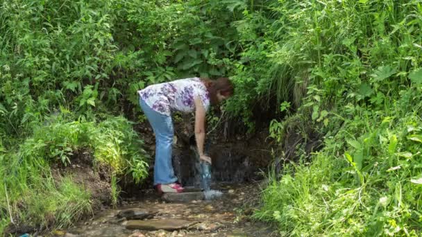 Kvinnan tar vatten från en källa — Stockvideo