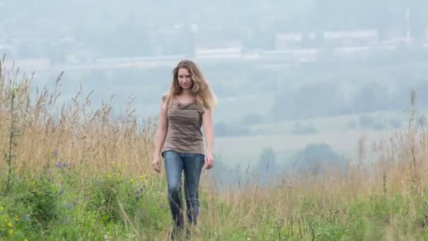 The girl in the field goes among a high yellow grass — Stock Video