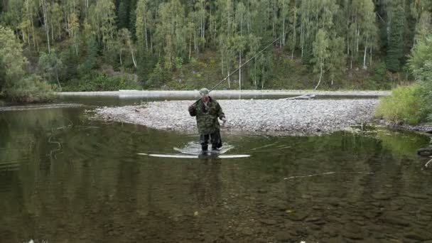 El pescador con la vara va al bosque por el río pequeño — Vídeos de Stock