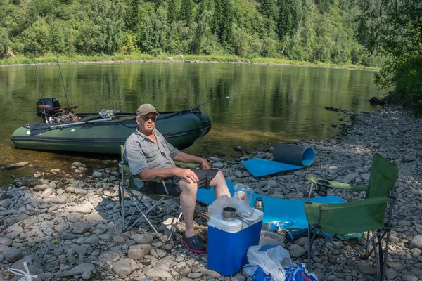 川の岸で釣りをした後に休んでいる漁師 ストック写真