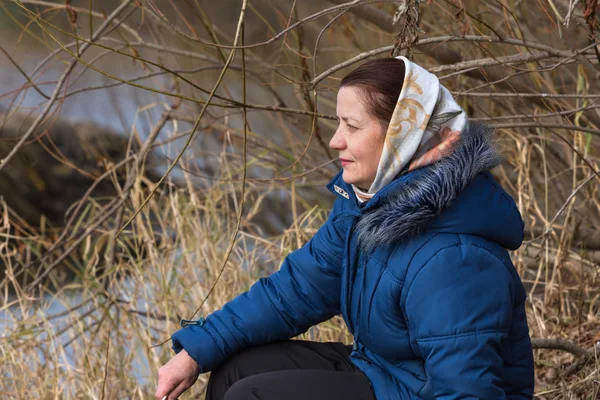Nehir kıyısında oturan kadın uzaktan görünüyor — Stok fotoğraf