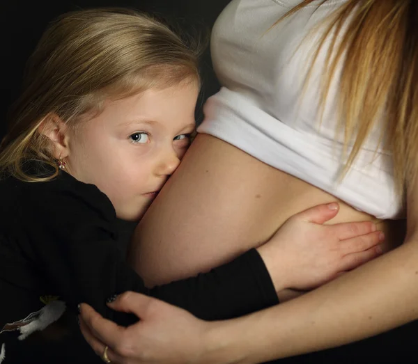 女孩拥抱母亲怀孕的肚子 — 图库照片