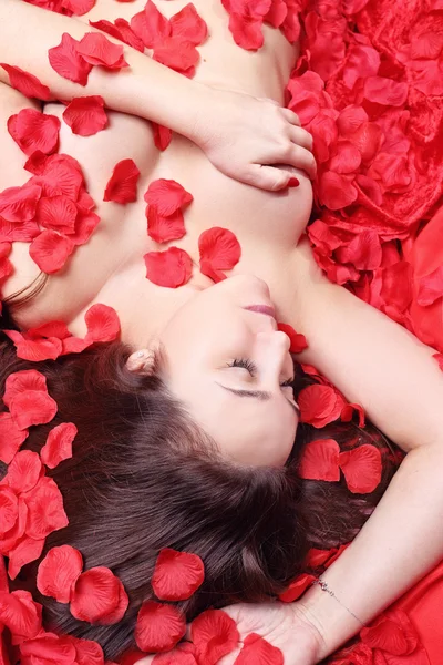 Jolie femme couchée dans des pétales de rose — Photo