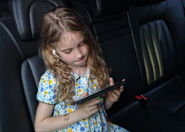 Menina viaja de carro e jogar em um tablet — Fotografia de Stock