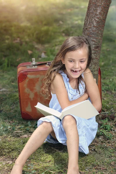 Lachendes junges Mädchen liest ein Buch — Stockfoto