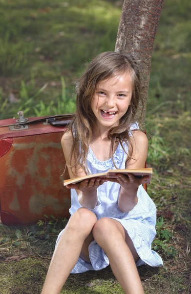 Delighted baby girl reads the reading in the park — Stock Photo, Image