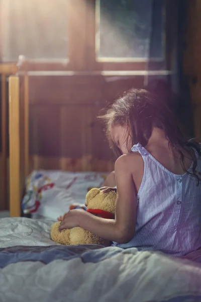 Distraught little girl cuddles a teddy bear — Stock Photo, Image