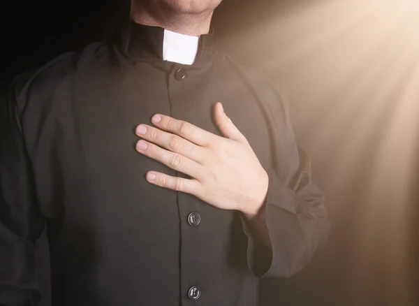 Betender Priester auf schwarzem Hintergrund — Stockfoto