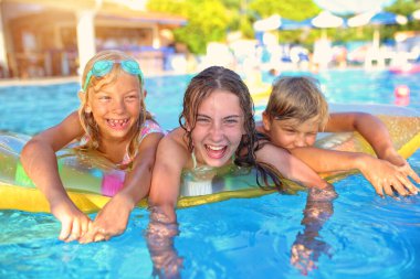 Çocuklar sıcak bir yaz gününde havuzda eğleniyor.