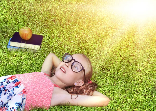 Back to school - happy girl with glasses on the grass — Stock Photo, Image
