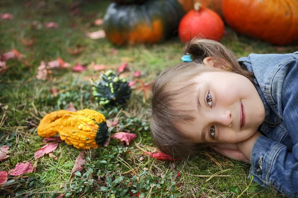 Szczęśliwa młoda dziewczyna lezala na ziemi z kolorowych dynie — Zdjęcie stockowe
