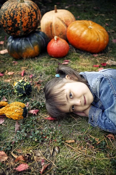 Jong meisje liggend op de grond met pumpkins — Stockfoto