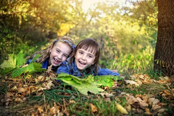 Girls lie under a tree with autumn leaves — Stock Photo, Image