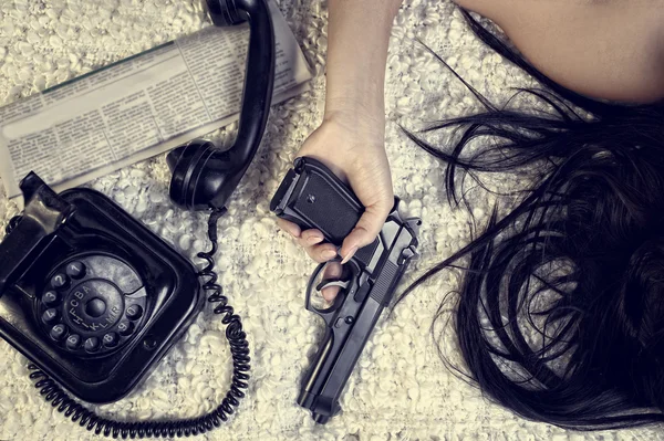 Girl with a gun lying on the bed — Stock Photo, Image