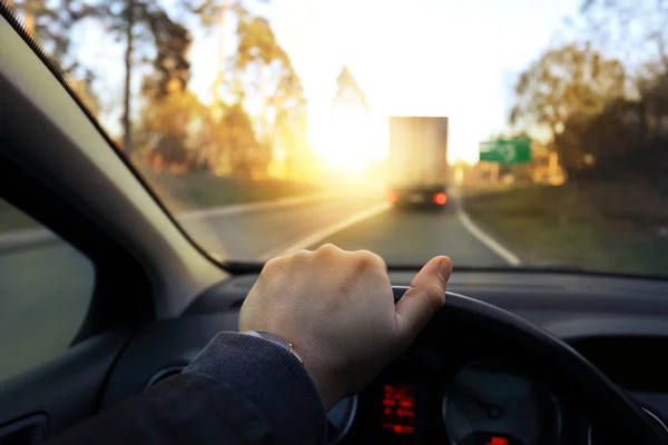 O motorista dirige o carro em uma tarde ensolarada — Fotografia de Stock