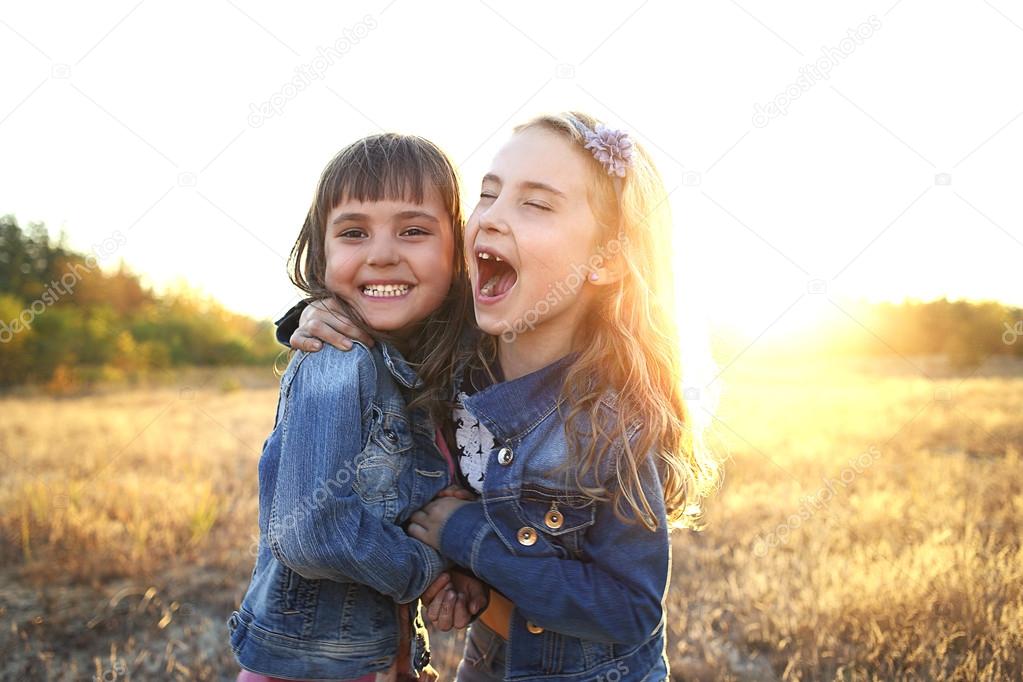 Two cheerful friends snuggling outdoors in the park