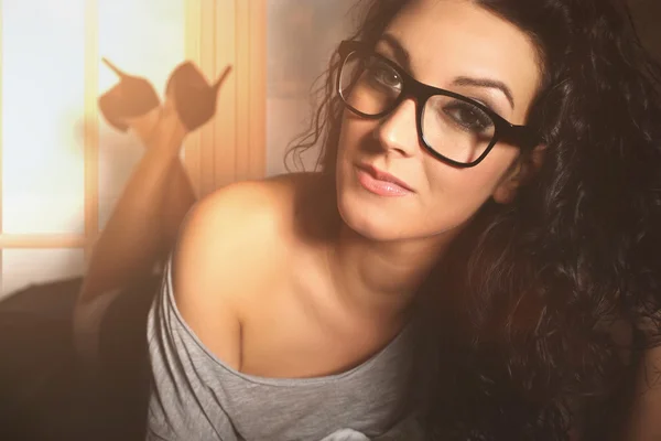 Smyslná krásná žena leží na posteli s brýlemi — Stock fotografie