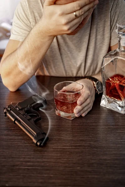Опустошённый мужчина с пистолетом и алкоголем — стоковое фото
