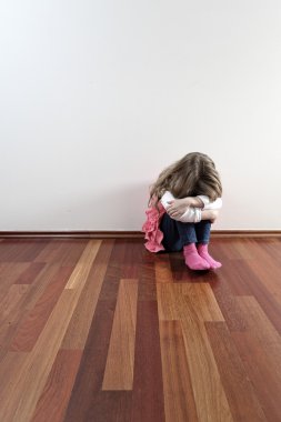 Sad lonely girl sitting against a wall clipart