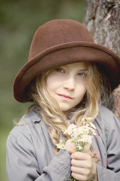 Ragazza in un cappello e mazzo di fiori — Foto Stock