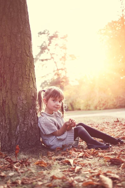 Jeune fille se couche sur les feuilles dans le parc d'automne — Photo