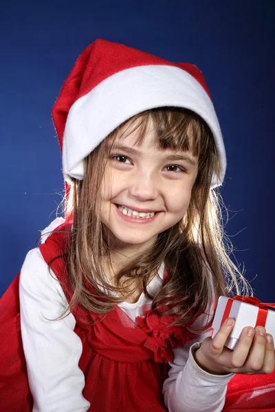 La chica en sombrero de santa con un regalo sobre un fondo azul — Foto de Stock