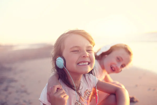 Chicas alegres escuchan música en una soleada playa de verano — Foto de Stock