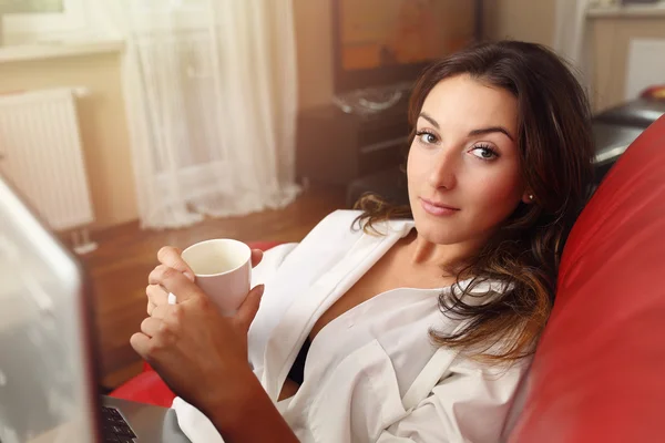 La chica bebiendo café de la mañana y trabajando en un portátil — Foto de Stock