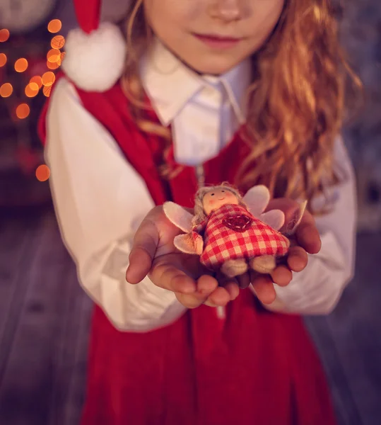 Niña pequeña sosteniendo una figura de un ángel en la mano en la víspera — Foto de Stock