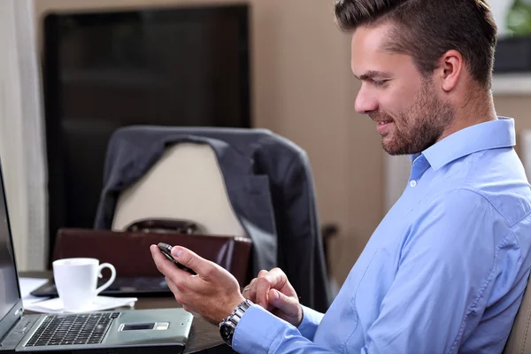 Jovem empresário verifica as mensagens no telefone em casa — Fotografia de Stock