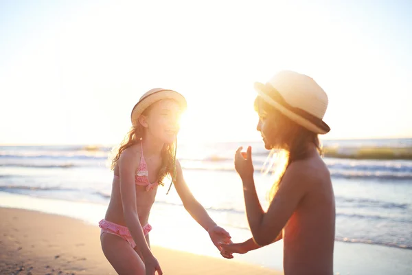 Amigos estão jogando na praia durante o pôr do sol — Fotografia de Stock