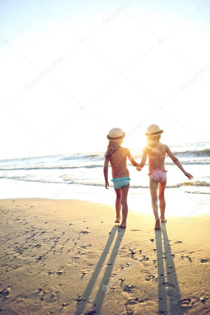 Young girls run toward the sea