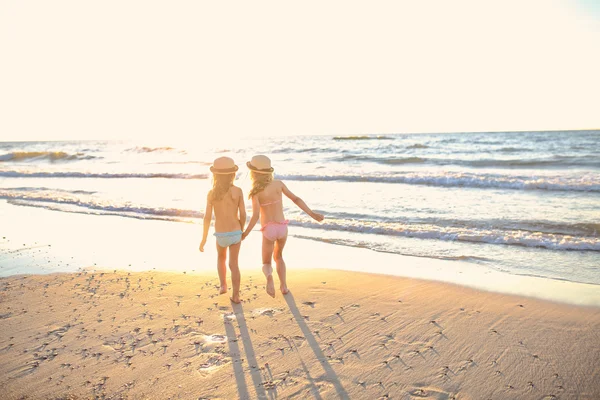 Irmãs maravilhosas estão indo à beira-mar em chapéus e são felizes — Fotografia de Stock