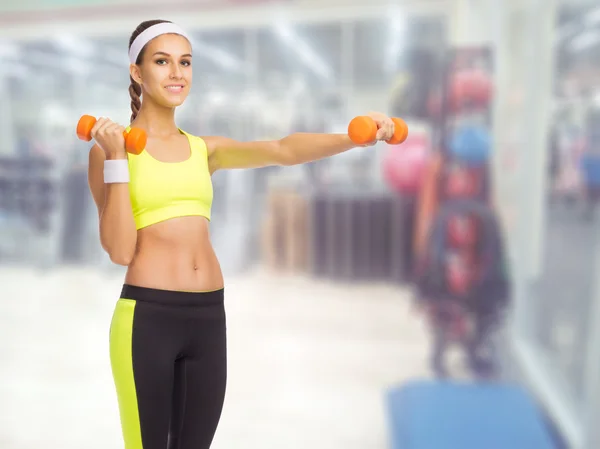 Sporty girl with dumbbells in fitness club — Stock Photo, Image