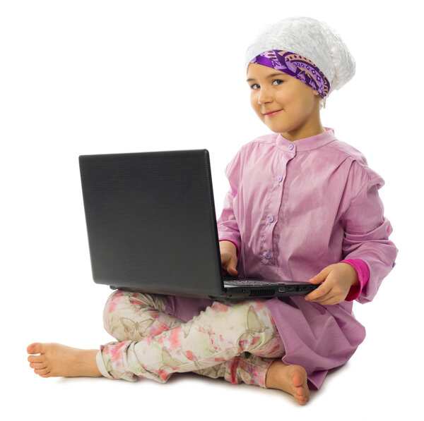 Маленькая девочка в традиционной мусульманской одежде с ноутбуком
