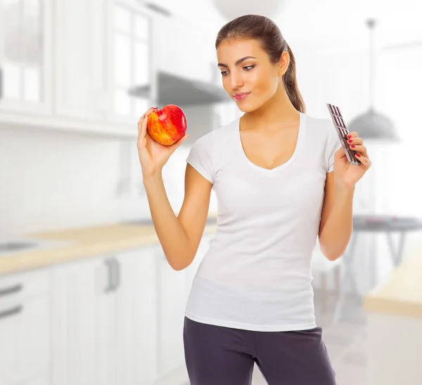 Girl with apple and chocolate at light kitchen — Stock Photo, Image