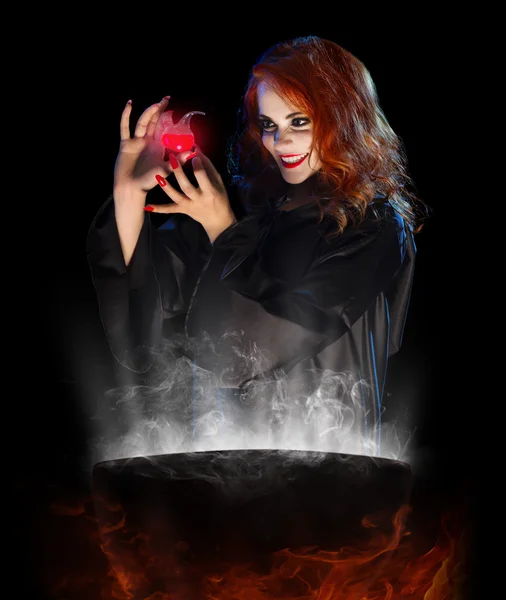 Young witch with red potion and cauldron — Stock Photo, Image