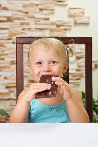 Kleines Mädchen mit Schokolade im hellen Raum — Stockfoto