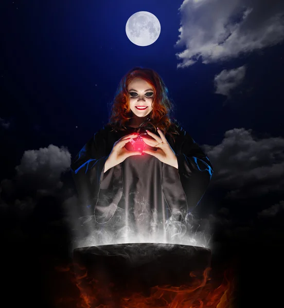 Witch with red potion and cauldron on night sky background — Stock Photo, Image