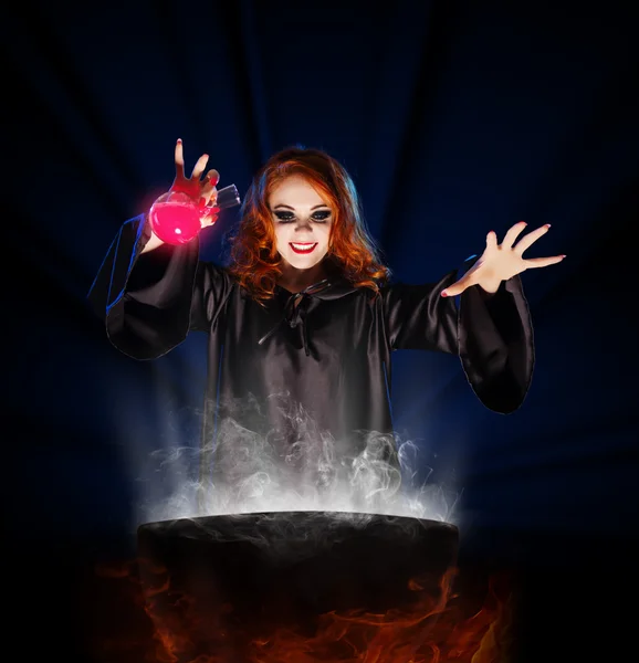 Witch with potion and cauldron on blue rays background — Stock Photo, Image