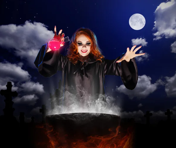 Witch with red potion and cauldron on night sky background — Stock Photo, Image