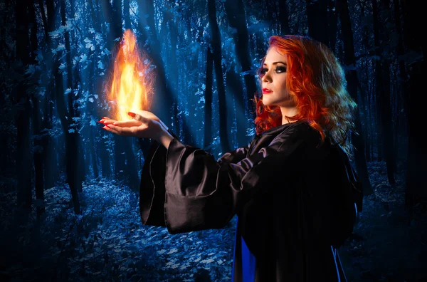 Witch in the night forest holds fire — Stock Photo, Image