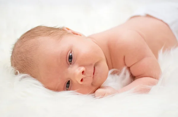 Baby lying on a fur bedspread — Stock Photo, Image