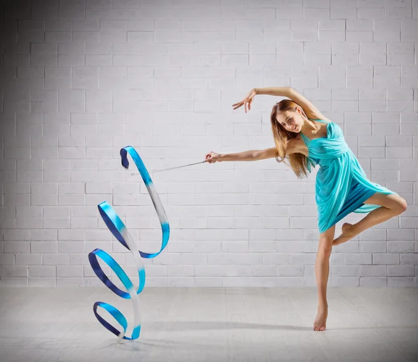 Menina está envolvida em arte ginástica na parede cinza — Fotografia de Stock