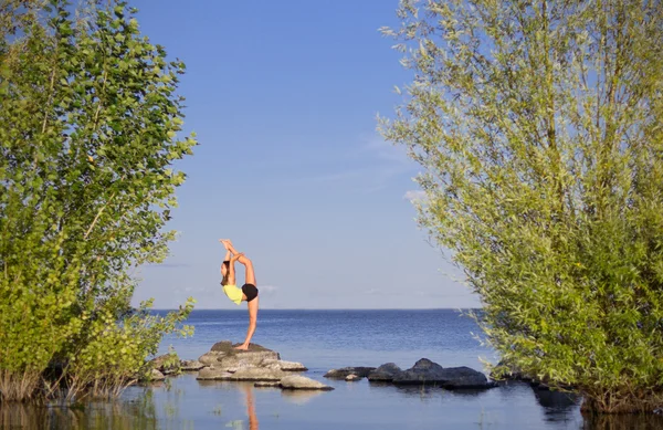 Chica haciendo ejercicios de gimnasia en la orilla del mar — Foto de Stock