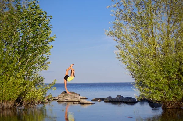 Chica haciendo ejercicios de gimnasia en la orilla del mar — Foto de Stock